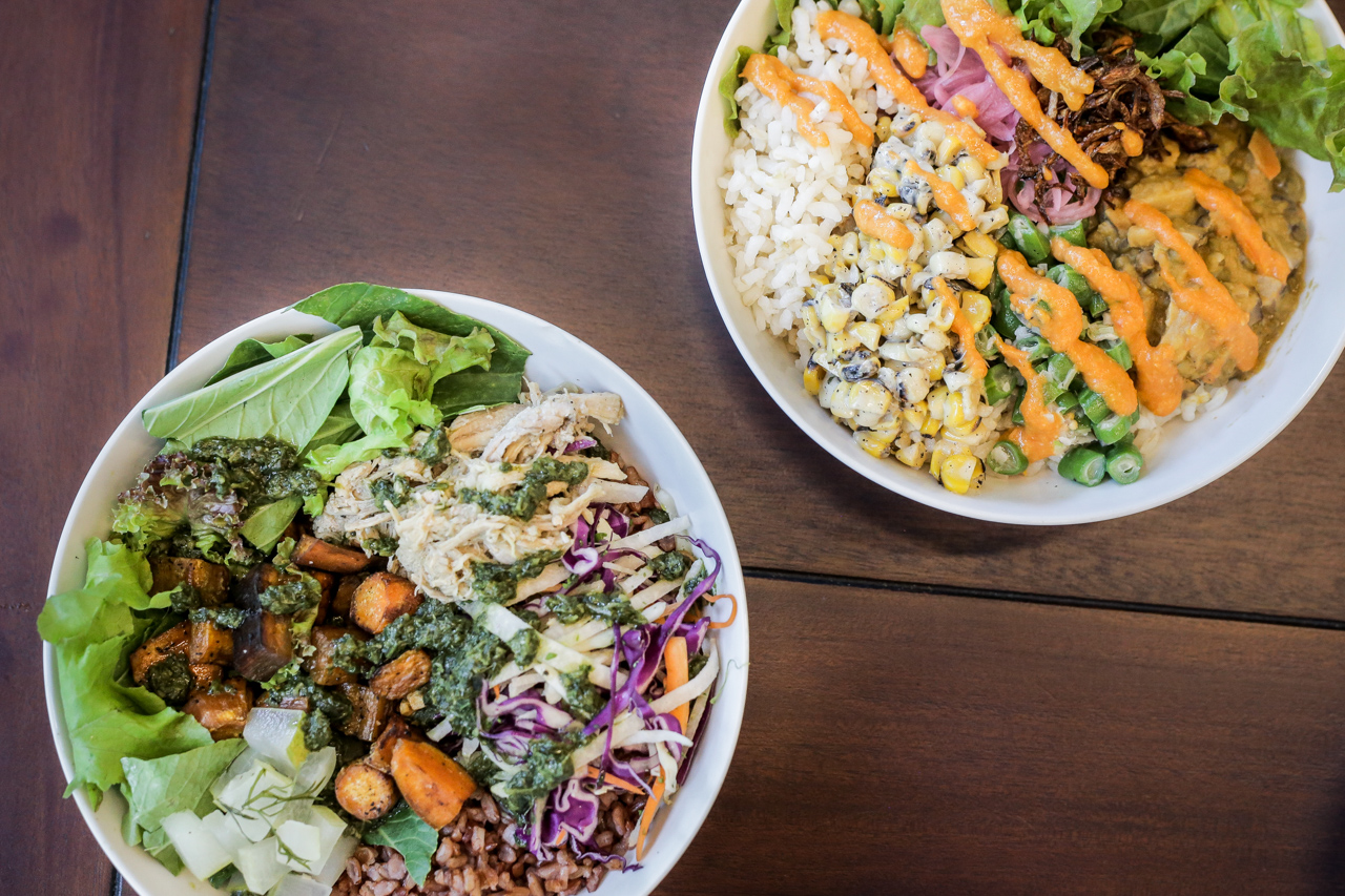 Top right: A customized mushroom monggo kare-kare bowl, with the addition of coconut pandan cream corn. Bottom left: A pork karnitas bowl, with red rice and Berde salad. It also has Radish and carrots, oven-roasted kamote, and cucumber and dill pickles. All topped with a basil-cilantro-parsley sauce