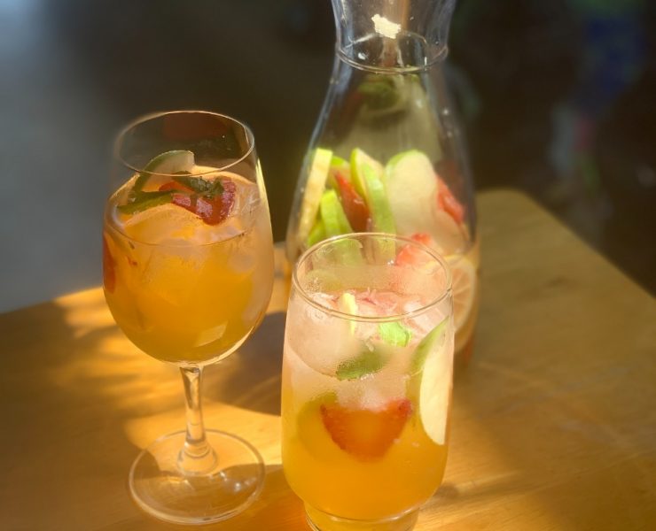 A photo of white wine sangria with apples, strawberry and lemons in a carafe and two glasses. Photo by Pauline Miranda for Nolisoli