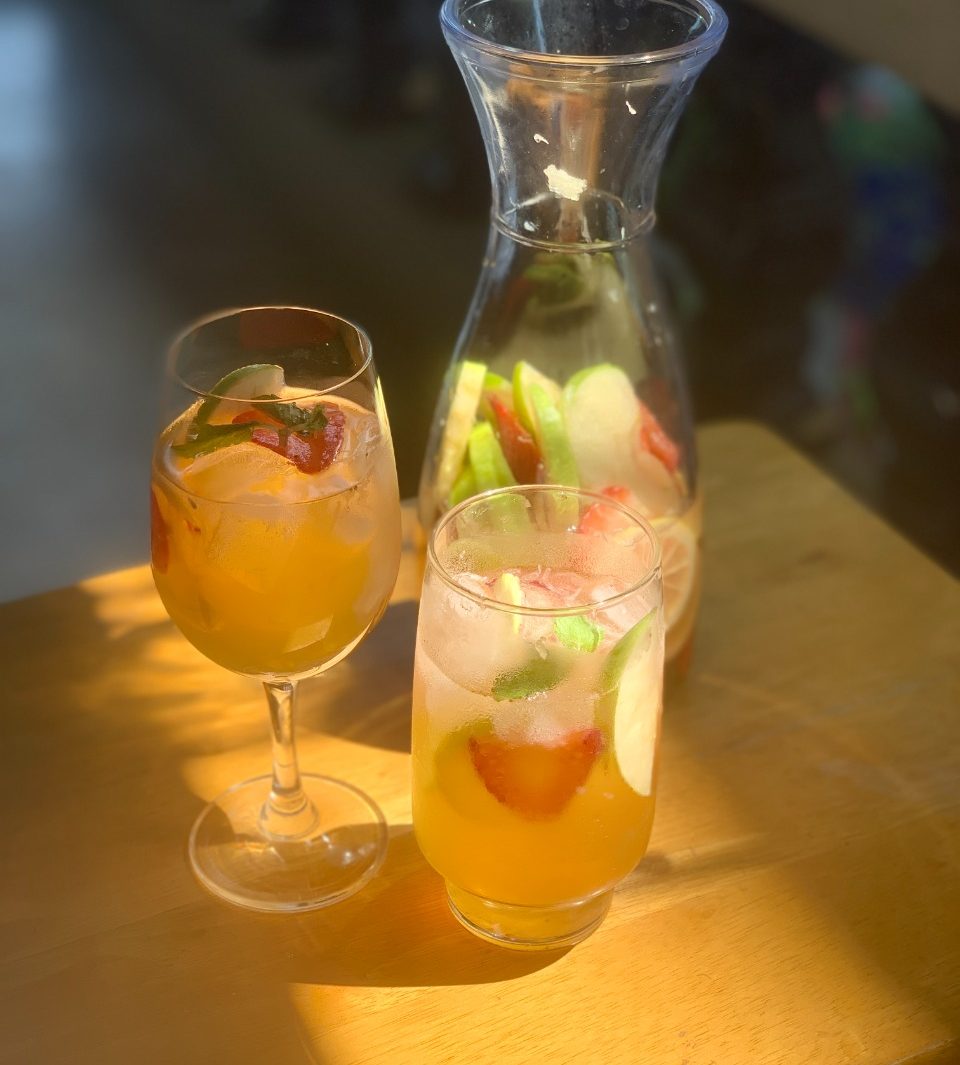 A photo of white wine sangria with apples, strawberry and lemons in a carafe and two glasses. Photo by Pauline Miranda for Nolisoli