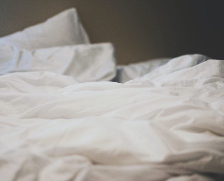 An unmade bed with white sheets