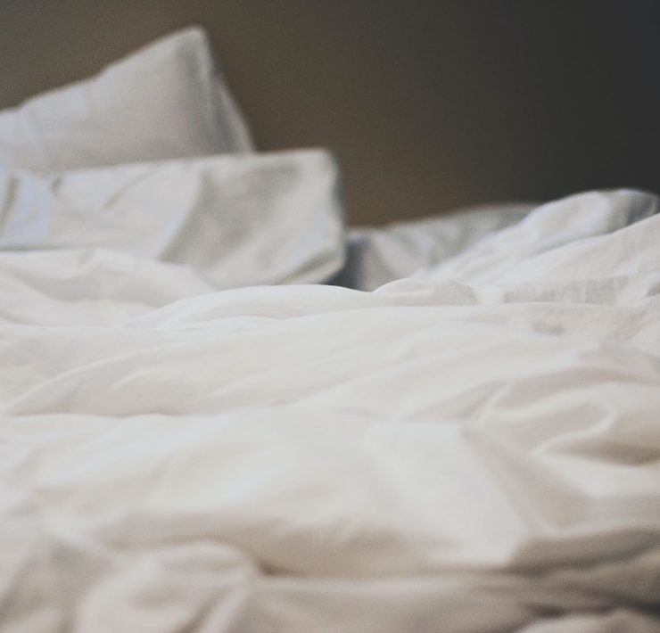 An unmade bed with white sheets