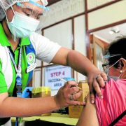an elderly woman being injected with covid-19 vaccine by a health worker