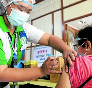 an elderly woman being injected with covid-19 vaccine by a health worker