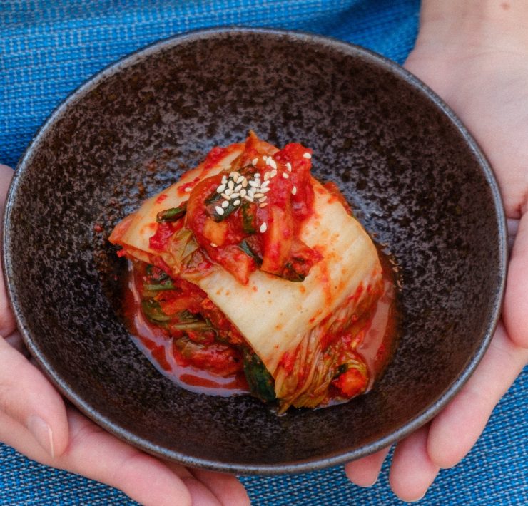 kimchi on a bowl held by two hands