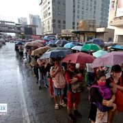commuters queueing in the rain to get into a bus in EDSA