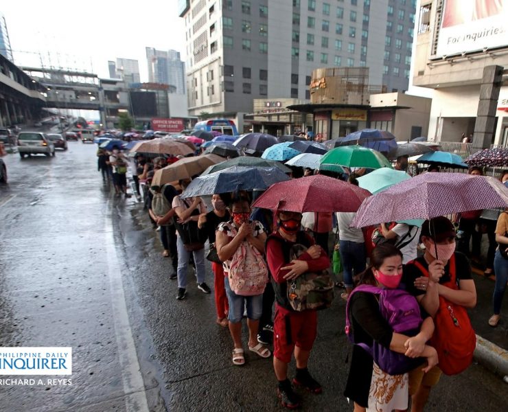 commuters queueing in the rain to get into a bus in EDSA