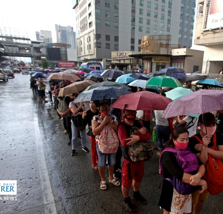 commuters queueing in the rain to get into a bus in EDSA