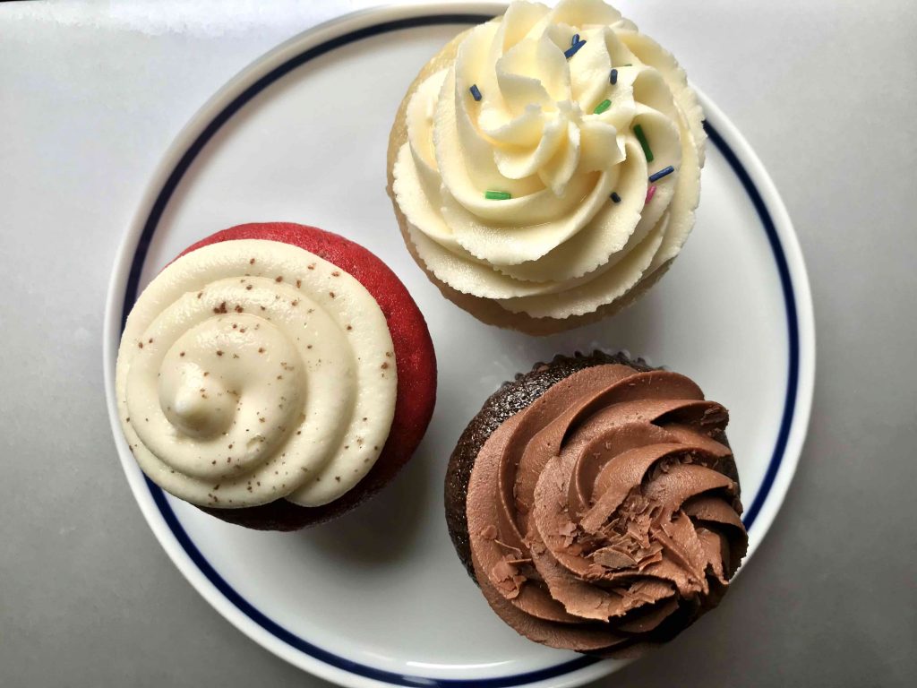 vegan red velvet, vanilla, and chocolate cupcakes on a plate