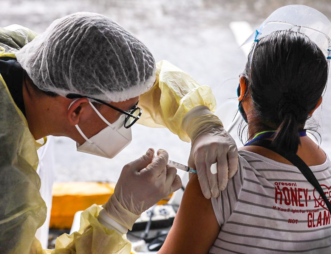 a medical worker injects a woman with covid-19 vaccine in novaliches quezon city