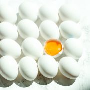 eggs stacked in a row with one in the middle cracked to expose the yolk