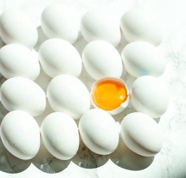 eggs stacked in a row with one in the middle cracked to expose the yolk