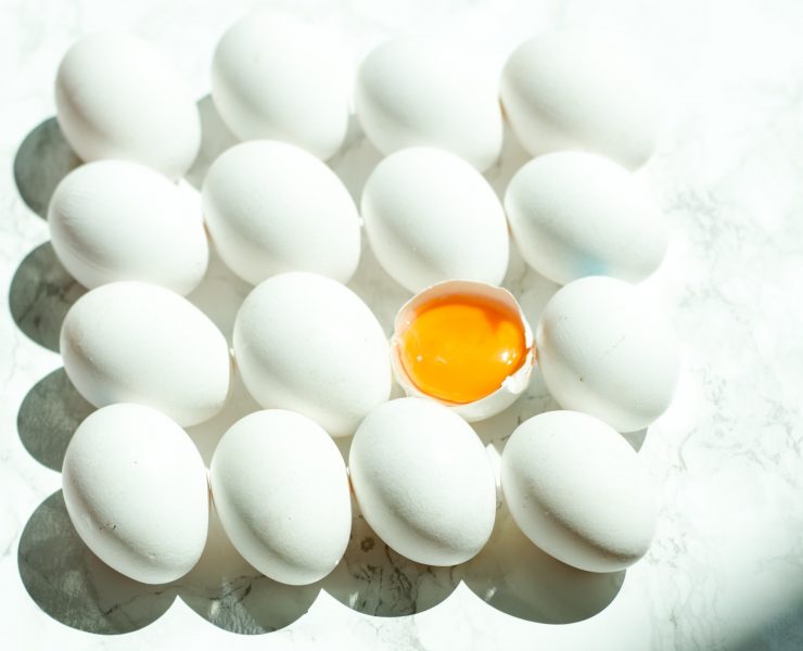 eggs stacked in a row with one in the middle cracked to expose the yolk
