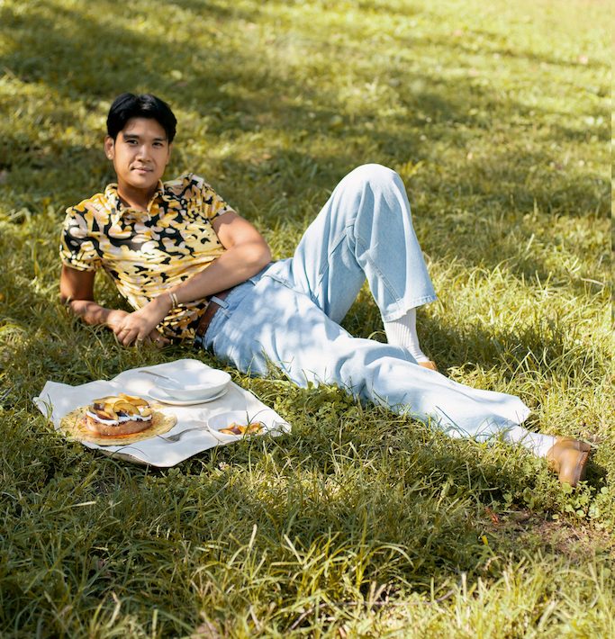 woldy reyes laying in the grass at fort green park in brooklyn with a baked good on a picnic cloth