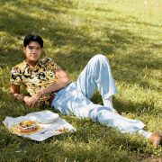 woldy reyes laying in the grass at fort green park in brooklyn with a baked good on a picnic cloth