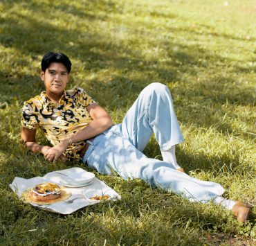 woldy reyes laying in the grass at fort green park in brooklyn with a baked good on a picnic cloth