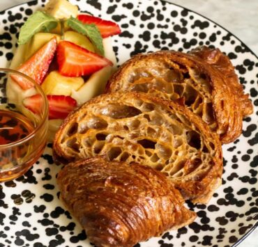 croissant french toast with pastry cream and fruits on a speckled plate