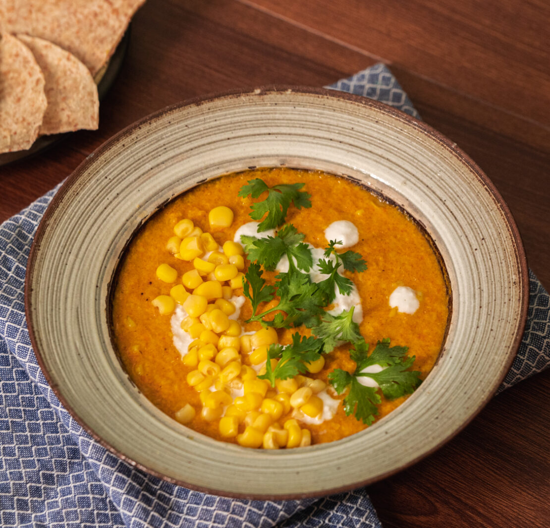 corn carrot soup on a bowl and a side of pita chips