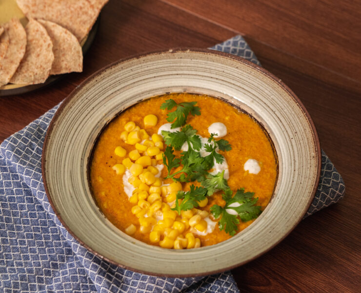 corn carrot soup on a bowl and a side of pita chips