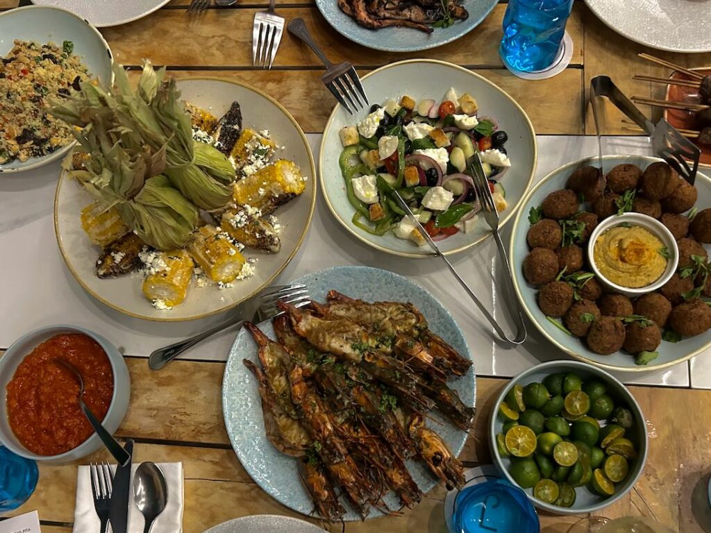 Clockwise from left: Mexican elote, tomato, basil, cucumber, and olive panzanella, beef koftas, and grilled fresh prawn